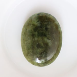 May include: A smooth, oval-shaped green stone with a mottled pattern. The stone has a polished finish and is a light green color.
