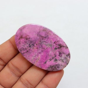 May include: A pink and black oval cabochon gemstone with a marbled pattern.