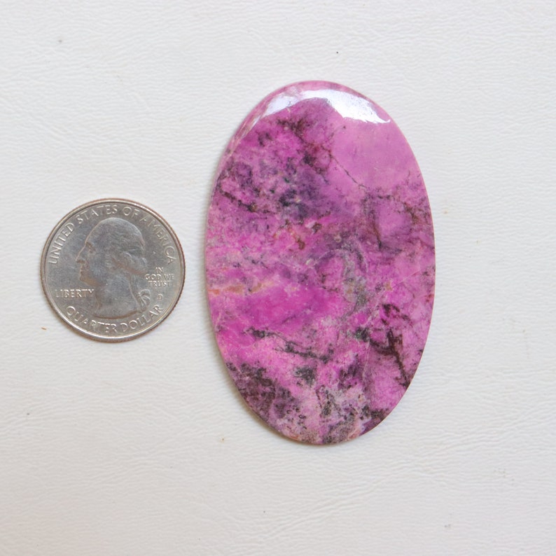 May include: A large, oval-shaped, pink and black cabochon gemstone. The gemstone has a swirling pattern of pink and black.
