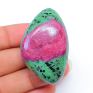 May include: A green and pink gemstone with a rough, natural finish. The stone has a green base with a pink, swirling pattern.