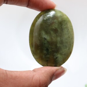 May include: A smooth, oval-shaped green stone with a mottled pattern. The stone is polished and has a glossy finish.
