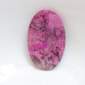 May include: A pink and grey oval cabochon gemstone with a marbled pattern.