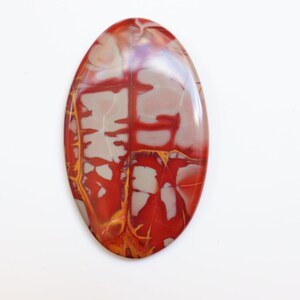 May include: A red, white, and yellow oval cabochon gemstone with a marbled pattern. The stone is polished and has a smooth surface.