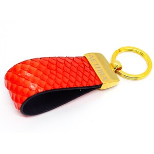 May include: Red leather keychain with a gold ring and the word "AETHIRA" engraved on the metal tag.