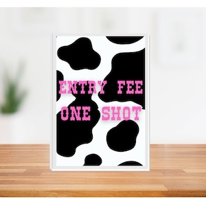 以下が含まれることがあります： 白と黒の牛柄の背景に、ピンク色の文字で「ENTRY FEE ONE SHOT」と書かれています。