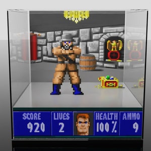 May include: A pixelated video game scene featuring a character in a tan uniform and blue boots, holding a weapon. The scene includes a barrel, treasure chest, and a health bar. The game is displayed inside a clear display case.