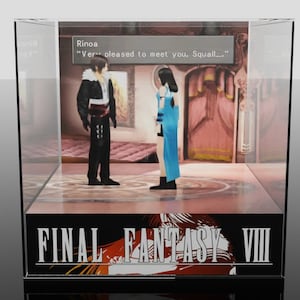 Puede incluir: Una vitrina de Final Fantasy VIII con dos personajes y el texto "Very pleased to meet you, Squall...". El logotipo del juego está en la parte inferior. La escena está dentro de una caja transparente.