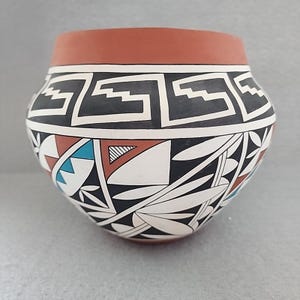 Puede incluir: Una taza de cerámica blanca con un asa negra y el texto "But First, Coffee" en negrita negra. La taza se encuentra sobre un fondo neutro, resaltando su diseño sencillo.