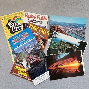 Pode incluir: Uma coleção de recordações de viagem vintage, incluindo postais e brochuras. Os itens apresentam as atrações de Lookout Mountain e Ruby Falls em Chattanooga, Tennessee. A paleta de cores inclui tons de amarelo, vermelho, azul e castanho.