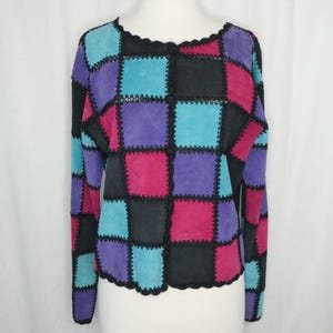 May include: A patchwork jacket with a checkerboard pattern. The jacket features squares of black, purple, pink, and turquoise suede, stitched together with black thread. The jacket has long sleeves and a scalloped neckline.
