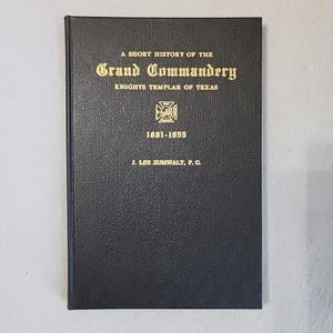 May include: A black hardback book with gold lettering reading "A Short History of the Grand Commandery Knights Templar of Texas." The cover includes a gold emblem and the dates 1881-1955. The author's name is also printed.