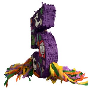 Puede incluir: Una pi&ntilde;ata con forma de n&uacute;mero cinco cubierta de papel con flecos morados, decorada con varios recortes de personajes que incluyen un perro fantasma blanco, un sombrero verde, un personaje femenino de pelo rojo largo y una calavera, con serpentinas.
