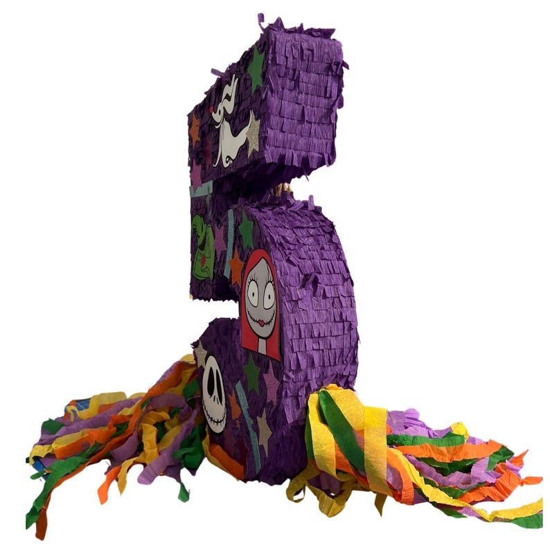 Puede incluir: Una pi&ntilde;ata con forma de n&uacute;mero cinco cubierta de papel con flecos morados, decorada con varios recortes de personajes que incluyen un perro fantasma blanco, un sombrero verde, un personaje femenino de pelo rojo largo y una calavera, con serpentinas.