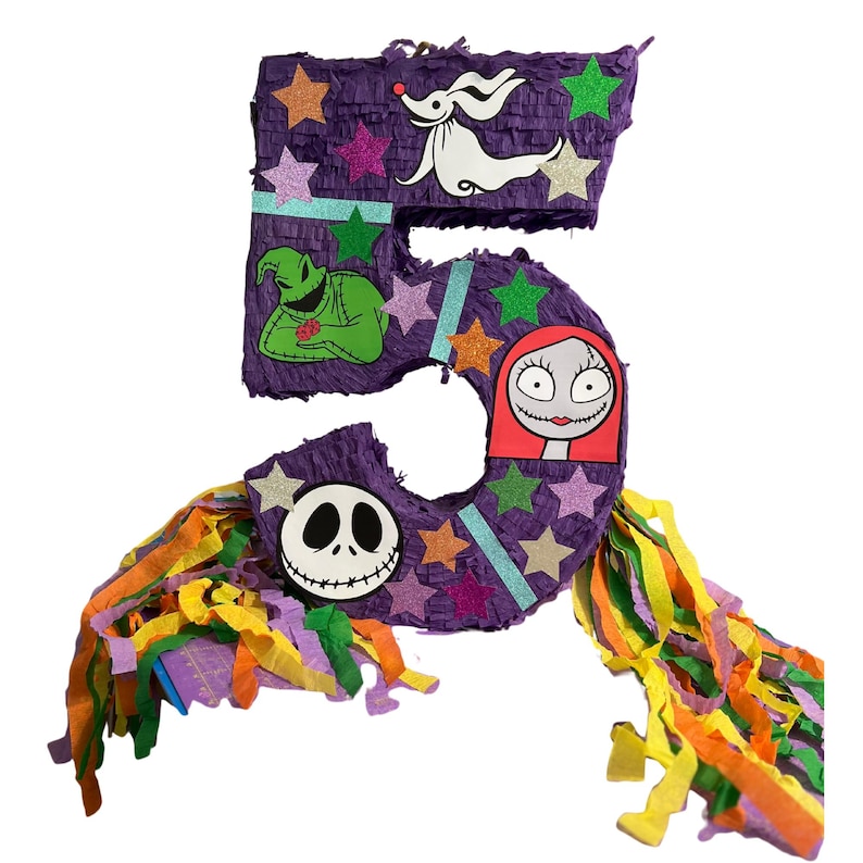 Puede incluir: Una pi&ntilde;ata con forma de n&uacute;mero cinco morado decorada con estrellas brillantes y recortes de personajes, incluyendo un perro fantasma blanco, una criatura verde, una cara cosida y un personaje femenino de pelo rojo. Cuelgan serpentinas de papel.