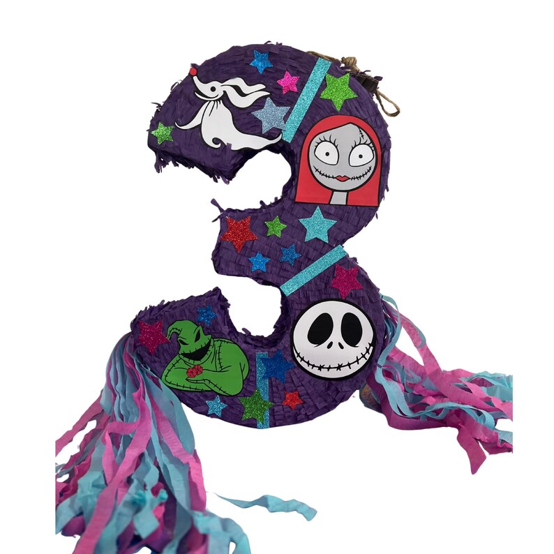 Puede incluir: Una pi&ntilde;ata con forma de n&uacute;mero tres de color morado decorada con estrellas brillantes y recortes de personajes que incluyen un perro fantasma blanco, una figura pelirroja, un monstruo verde y una calavera blanca con tiras de papel.
