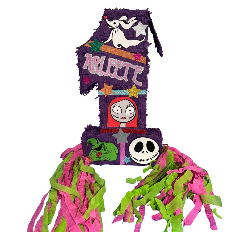 Puede incluir: Una pi&ntilde;ata con forma de n&uacute;mero uno en color morado, decorada con estrellas brillantes y personajes de Pesadilla antes de Navidad. El nombre Arleete est&aacute; escrito en letras rosas con purpurina. La base tiene tiras de papel verde lima y rosa.