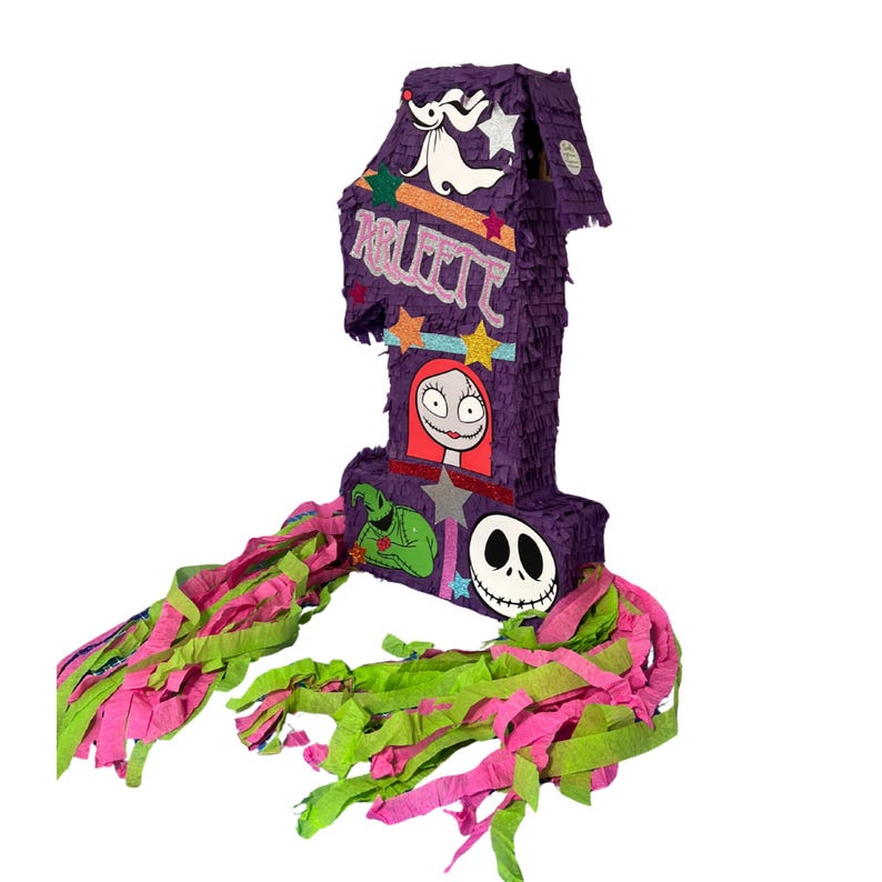 Puede incluir: Una pi&ntilde;ata con forma de n&uacute;mero uno en color morado, decorada con el nombre Arleth en purpurina rosa, con recortes de Zero, Sally, Oogie Boogie y Jack Skellington, acentuada con estrellas coloridas y largas tiras de papel rosa y verde.
