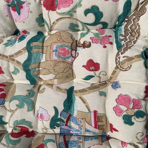May include: A cream-coloured fabric with a repeating pattern of green, brown, and pink floral designs. The pattern also includes an elephant, a monkey, and a tower.
