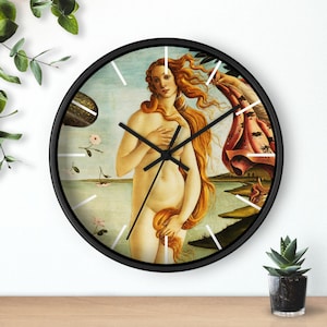 May include: A black framed wall clock with a white background and a painting of a nude woman with long flowing red hair. The clock hands are black and white.