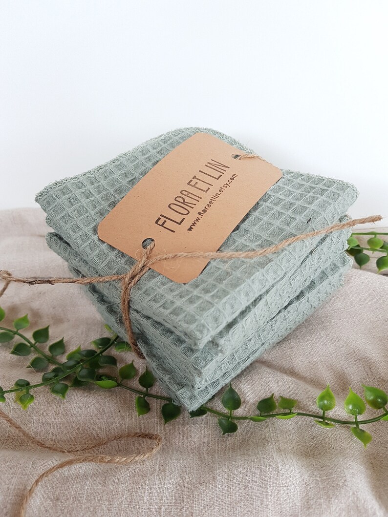 Pu&ograve; includere: Un set di quattro asciugamani da cucina in tessuto a nido d'ape verde salvia, legati con spago e un'etichetta marrone su cui &egrave; scritto "FLORA ET LIN" e "www.floraetlin.etsy.com".