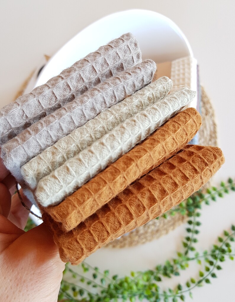 May include: A stack of four waffle weave fabric squares in beige, light green, and brown.