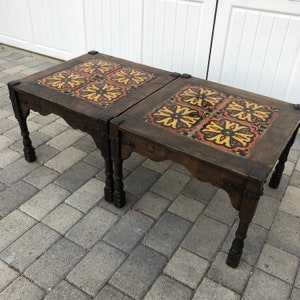 May include: Two wooden coffee tables with intricate tile inlays. The tiles are a mix of yellow, orange, and black. The tables have a dark wood finish and are supported by four legs.