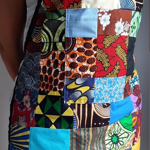 Peut inclure: Un tablier patchwork coloré avec une variété de tissus et de motifs, y compris des motifs floraux, géométriques et abstraits. Le tablier est en coton et possède une sangle réglable noire.