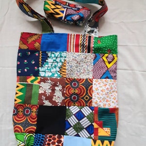 Può includere: Una borsa tote patchwork colorata con un motivo blu, verde, rosso, giallo e nero. La borsa ha una tracolla lunga e una piccola tasca attaccata alla tracolla. La tasca ha il testo "Dorothy May" stampato su di essa.