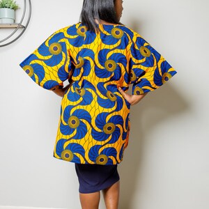 May include: A yellow and blue patterned kimono with a long sleeve and a loose fit. The kimono has a swirling pattern with blue and yellow circles.