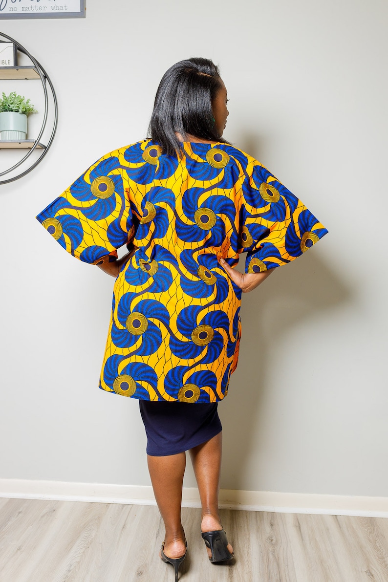 May include: A yellow and blue patterned kimono with a long sleeve and a loose fit. The kimono has a swirling pattern with blue and yellow circles.