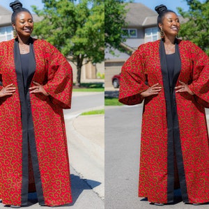 May include: A long red and gold patterned kimono with black trim and a black inner lining. The kimono has long sleeves and a front opening.