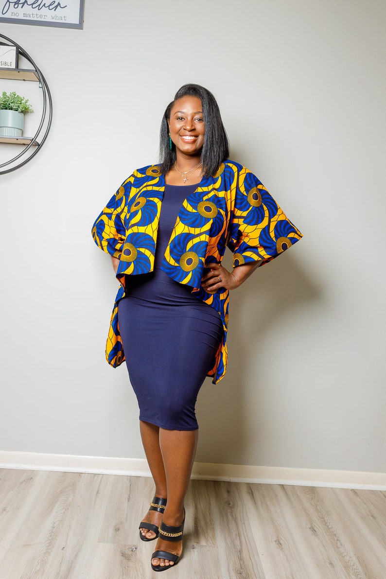 May include: A woman wearing a blue and yellow patterned kimono with a navy blue dress and black heeled sandals. The kimono has a floral design with gold accents.