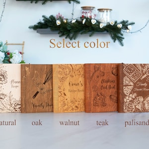 May include: Five wooden recipe books in different wood finishes: natural, oak, walnut, teak, and palisander. Each book has a unique design and text, including "Hann Recipe", "Family Recipe", "Oma's Recipe Book", "Christmas Cook Book", and "Family Favorite Recipes".