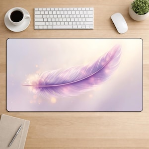 May include: A rectangular mouse mat with a digitally rendered, soft, purple feather. The feather is the central focus, set against a gradient background of light purple and gold. The mat is on a wooden desk with a keyboard, mouse, coffee cup, and plant.