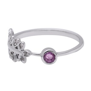 May include: A silver ring with a delicate leaf design set with small clear stones and a single round purple gemstone.