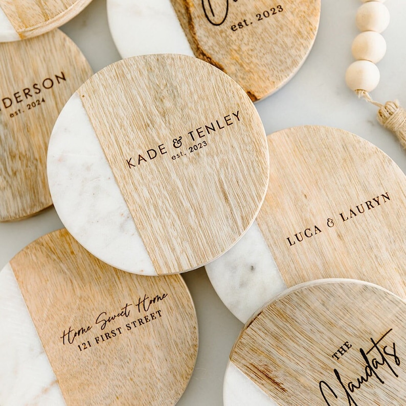 Puede incluir: Conjunto de seis posavasos redondos de madera con incrustaciones de m&aacute;rmol. Cada posavasos tiene una inscripci&oacute;n personalizada con un nombre y el a&ntilde;o "est. 2023".
