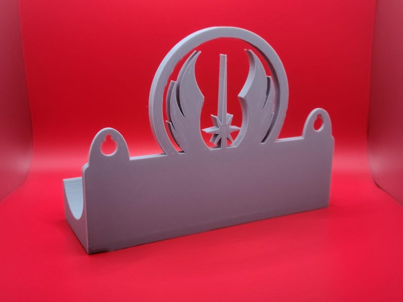 Puede incluir: Un soporte de pared de pl&aacute;stico gris con un recorte del s&iacute;mbolo de la Alianza Rebelde de Star Wars. El soporte tiene dos agujeros para colgar.