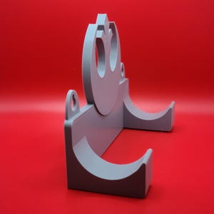 May include: A gray plastic wall mount with a Rebel Alliance symbol and two curved slots for holding items.
