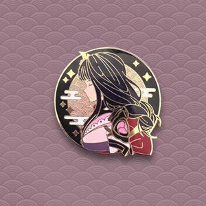 May include: A gold and black enamel pin featuring a woman with long black hair, wearing a pink and red kimono. The pin is set against a background of gold and black clouds and stars.