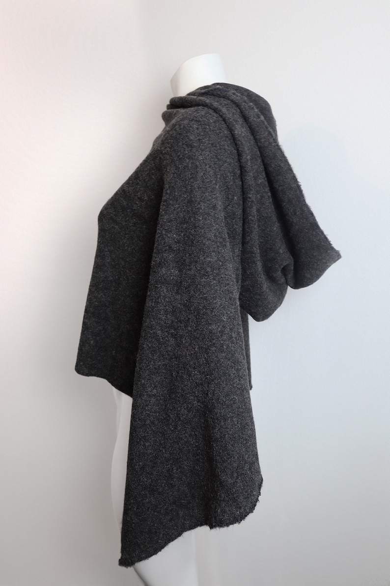 K&ouml;nnte beinhalten: Ein anthrazitfarbener Kapuzenpullover mit lockerer Passform und leicht verk&uuml;rzter L&auml;nge. Der Pullover hat eine weiche, flauschige Textur und eine lockere, flie&szlig;ende Silhouette.