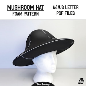 以下が含まれることがあります： キノコの形をした帽子を作るための黒いフォームハットパターン。パターンはA4/USレターサイズの紙に印刷されており、PDFダウンロードとして入手できます。帽子は白いマネキンヘッドに載せられています。