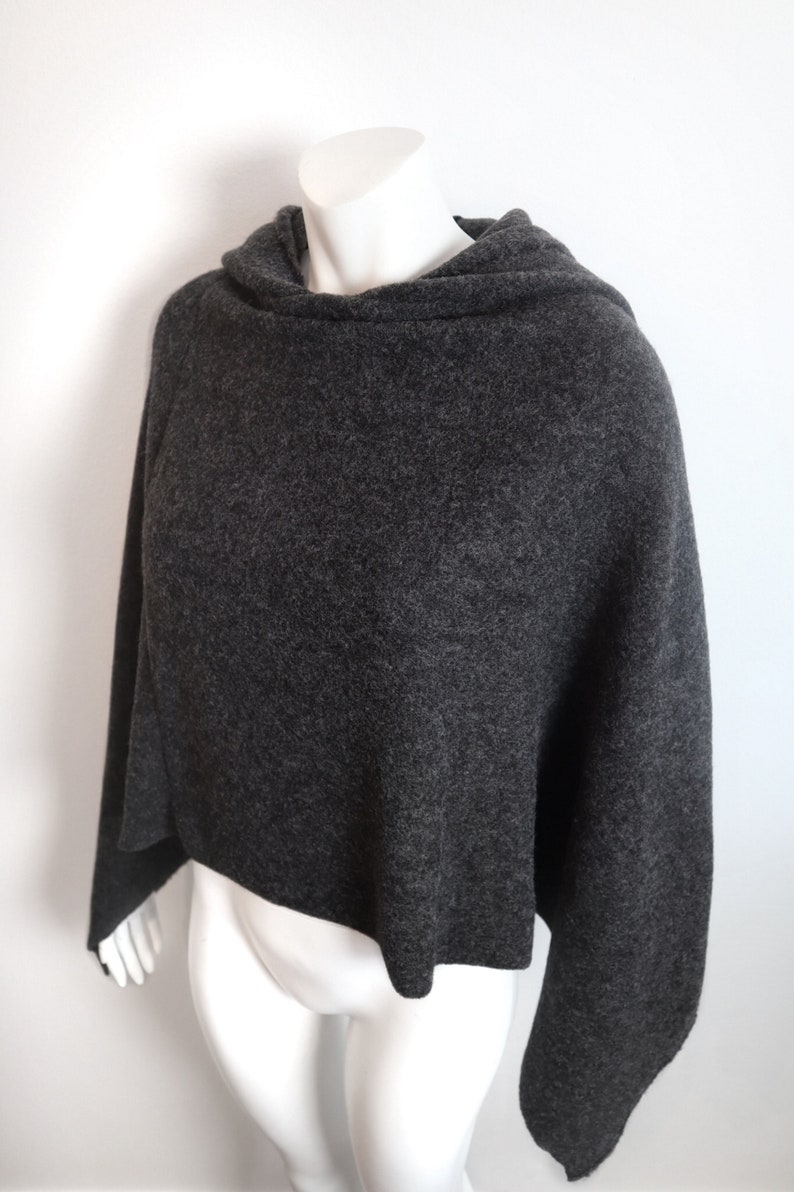 K&ouml;nnte beinhalten: Ein grauer Strickponcho mit einem Rollkragen.
