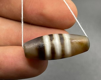 May include: A brown and white striped agate bead with a white string threaded through it.