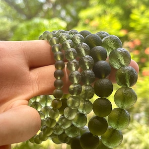 Op de afbeelding: Vier groene glazen kralen armbanden gestapeld op elkaar. De kralen zijn rond en hebben een getextureerd oppervlak.