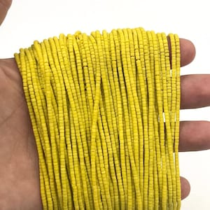 Peut inclure: Un brin de perles de verre jaune vif. Les perles sont petites et cylindriques, et elles sont enfilées sur un fil transparent.