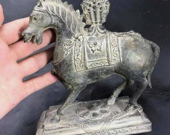 May include: A bronze statue of a horse with intricate details. The horse is standing on a base with a floral design. The horse is wearing a saddle and has a decorative headpiece.