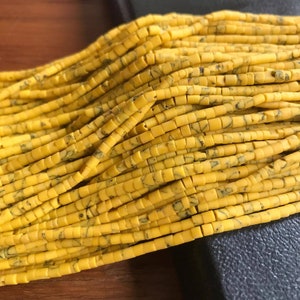 May include: A strand of yellow and black marbled round beads. The beads are approximately 6mm in diameter and have a smooth, polished finish.