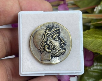 May include: A silver and gold coin with a profile of a man with a laurel wreath on his head. The coin is in a white display case.