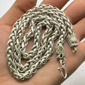 May include: A silver chain necklace with dragon head clasps. The chain is a braided design.