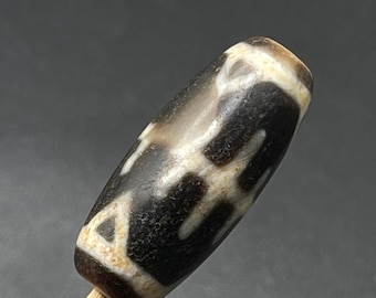 May include: A dark brown and white agate bead with a unique pattern. The bead is oval shaped and has a smooth, polished surface.